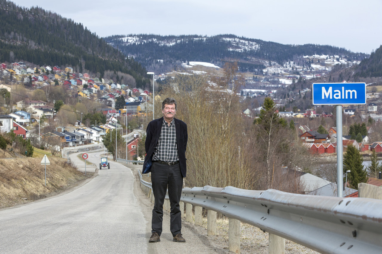 Frank Christiansen står på veien ved kommuneskiltet til Malm