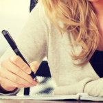 bildet viser en kvinne som skriver med penn i en bok
