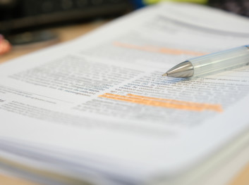 en penn ligger på en bunke papirer som ser ut som en vitenskapelig artikkel
